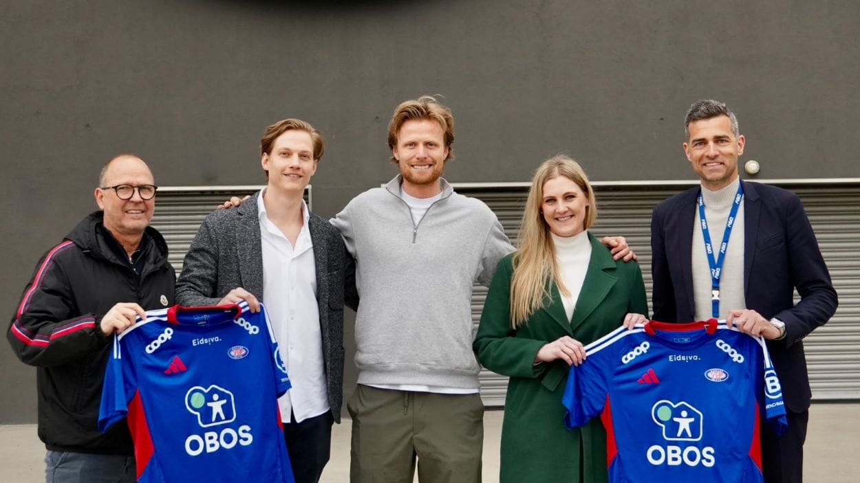 Fire ansatte fra DSV og en fra Vålerenga viser frem to fotballdrakter